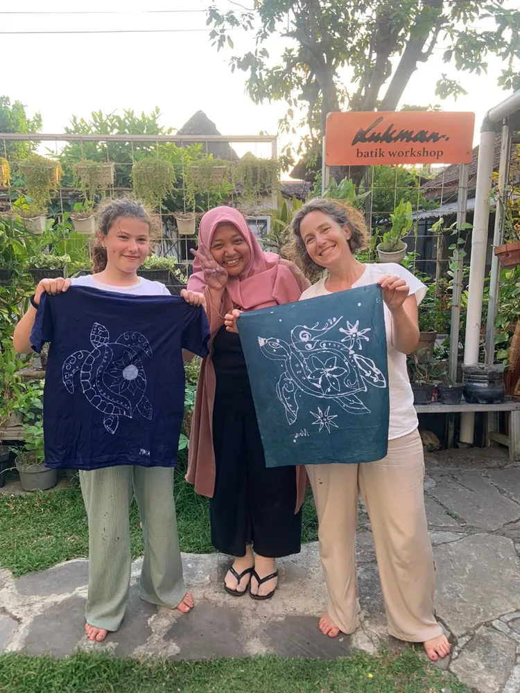 Guests with a studio artisan and their finished batik