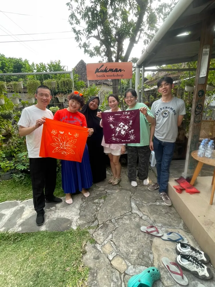 A group holding finished batik in warm and deep tones