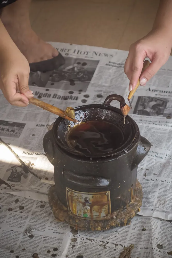 Dipping a canting into the pot of hot wax
