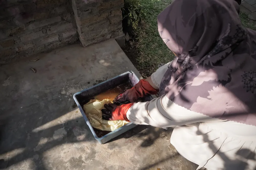 Lifting a cloth out of a natural dye bath in the studio garden